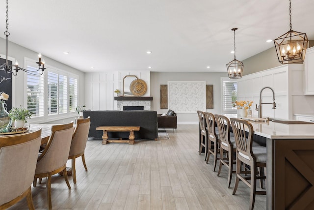 dining area featuring light wood-type flooring, recessed lighting, and a stone fireplace