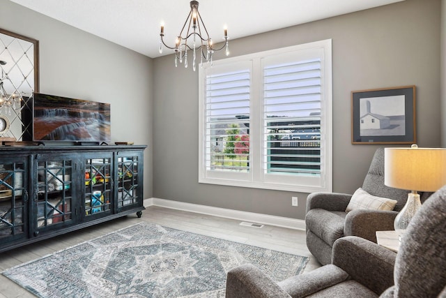 sitting room with an inviting chandelier, visible vents, baseboards, and wood finished floors