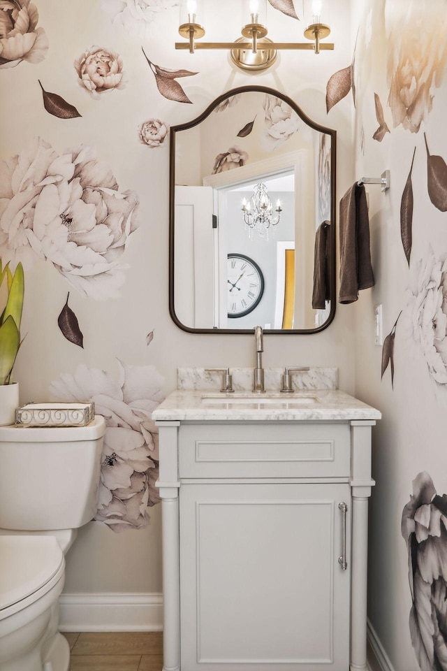 half bathroom featuring baseboards, vanity, and toilet