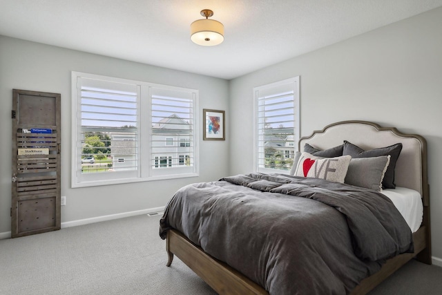 carpeted bedroom featuring multiple windows and baseboards