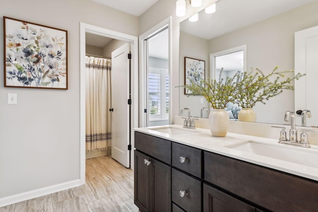 full bathroom featuring double vanity, baseboards, and a sink