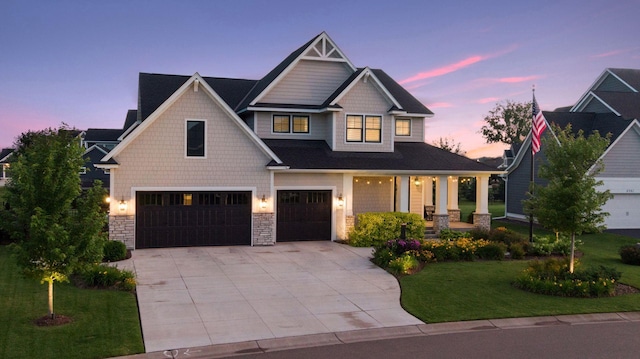 craftsman-style home with a porch, a garage, stone siding, driveway, and a front lawn