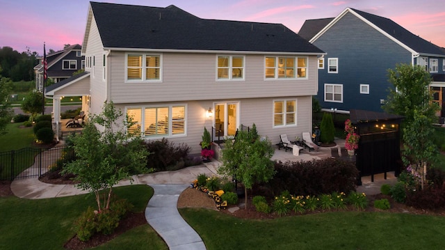 rear view of property featuring a patio area, a yard, and fence