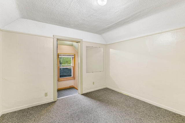 empty room featuring carpet flooring, a textured ceiling, and lofted ceiling