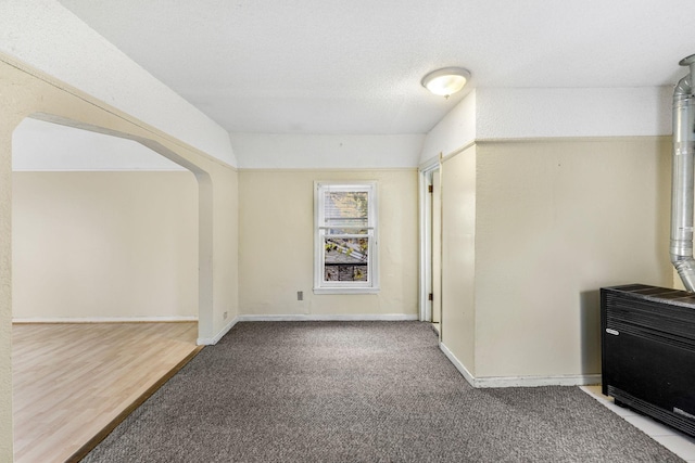 hallway with a textured ceiling, carpet floors, and lofted ceiling