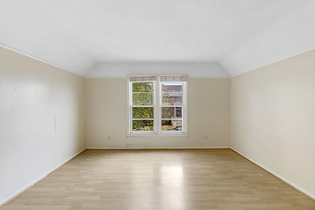 spare room with light wood-type flooring and lofted ceiling