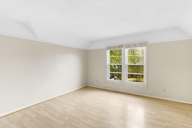 spare room with light hardwood / wood-style flooring and vaulted ceiling