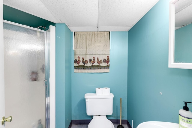 bathroom with a paneled ceiling, toilet, and an enclosed shower