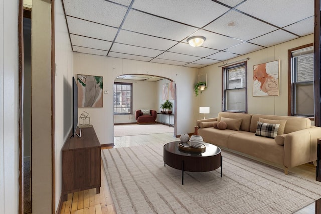 interior space featuring arched walkways, a drop ceiling, and light wood-style flooring