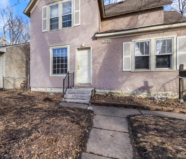 entrance to property with fence and stucco siding