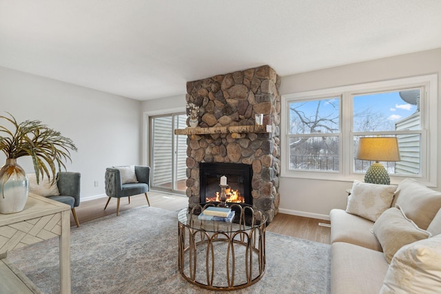 living room with hardwood / wood-style flooring, a wealth of natural light, and a stone fireplace