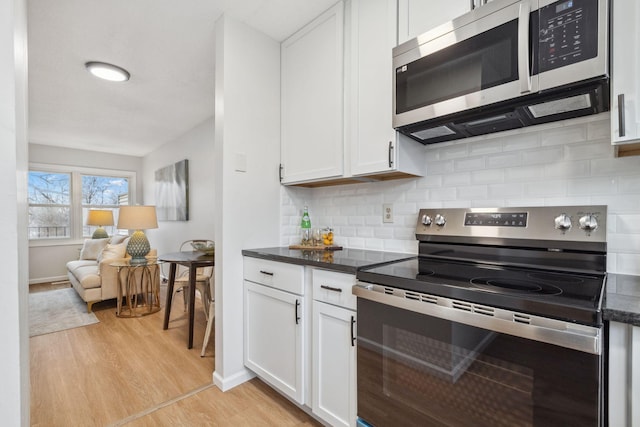 kitchen with backsplash, white cabinets, light wood-type flooring, and appliances with stainless steel finishes