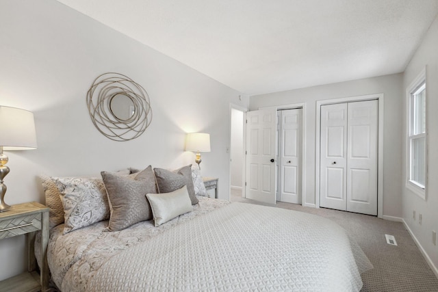 bedroom with carpet, multiple windows, and two closets