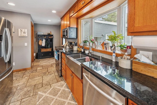 kitchen featuring recessed lighting, stone tile floors, baseboards, appliances with stainless steel finishes, and brown cabinets