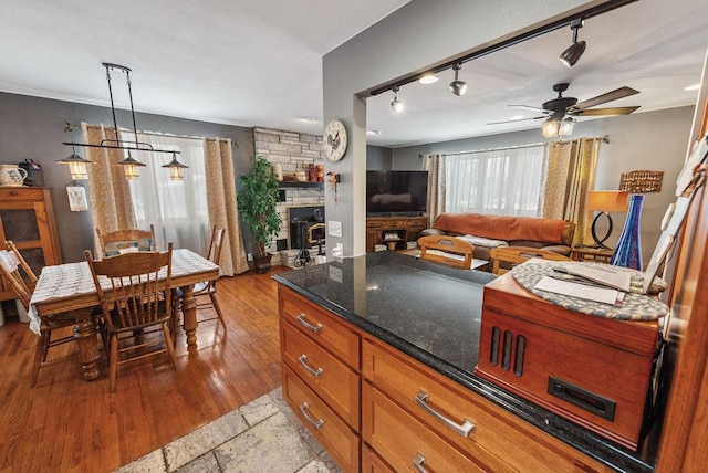 kitchen featuring plenty of natural light, brown cabinetry, a fireplace, and light wood-style floors