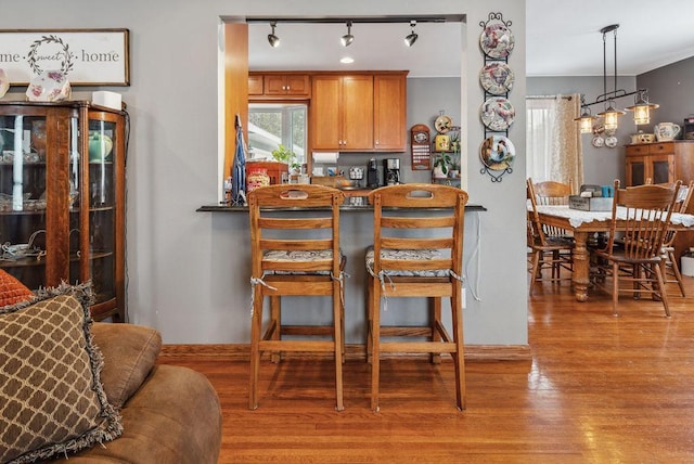 kitchen featuring rail lighting, brown cabinets, a kitchen breakfast bar, and wood finished floors