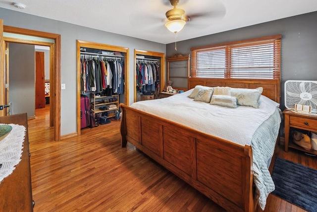 bedroom featuring light wood-type flooring, ceiling fan, baseboards, and multiple closets