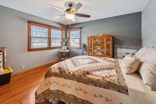 bedroom featuring a textured ceiling, ceiling fan, wood finished floors, and baseboards