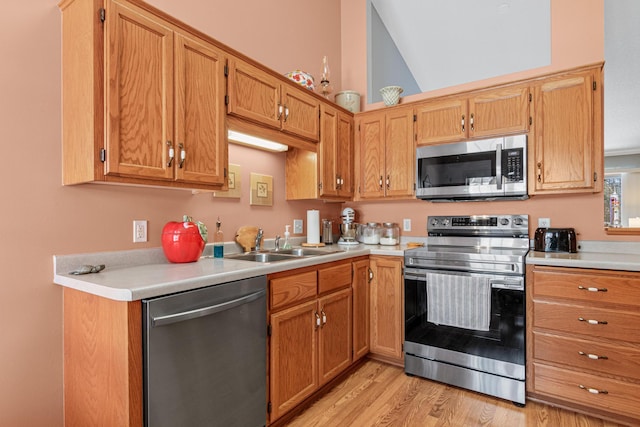 kitchen featuring sink, stainless steel appliances, light hardwood / wood-style flooring, and lofted ceiling