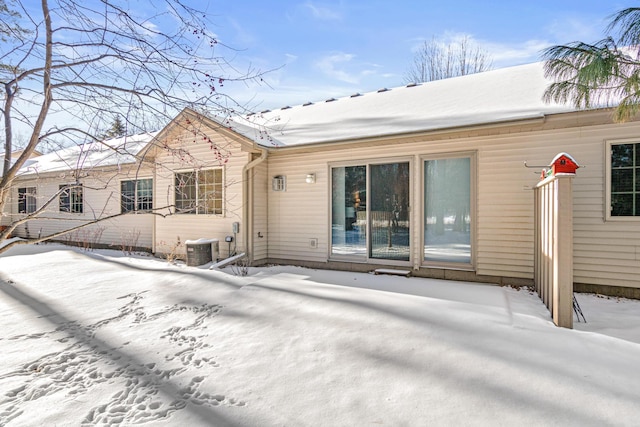 snow covered house featuring central AC unit