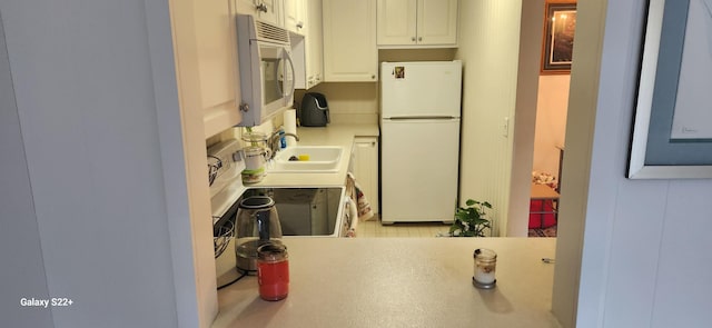 kitchen with white cabinets, sink, and white appliances