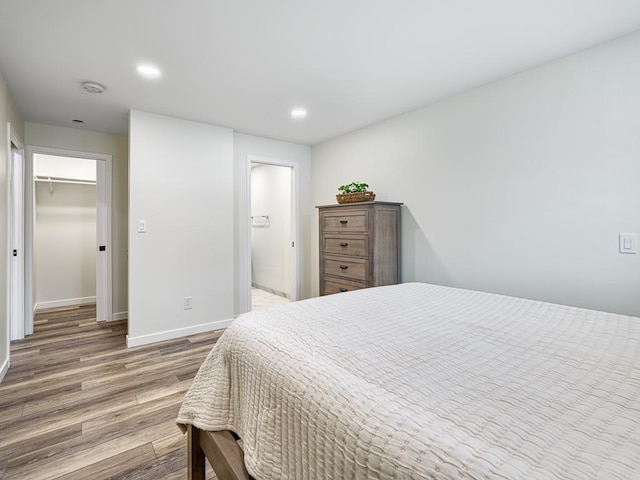 bedroom featuring a walk in closet, a closet, and hardwood / wood-style floors