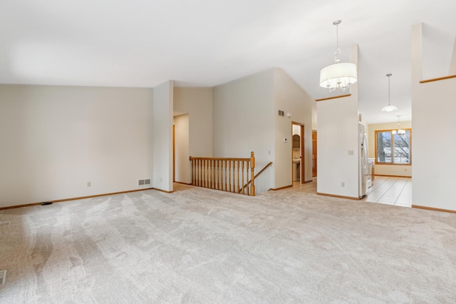 spare room featuring light carpet, vaulted ceiling, and a notable chandelier