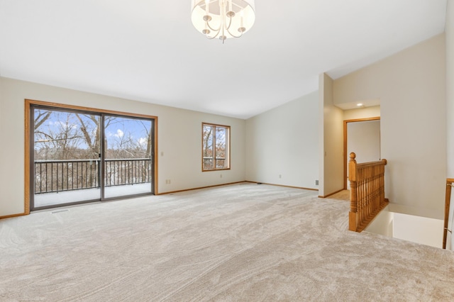 carpeted empty room with lofted ceiling and a notable chandelier