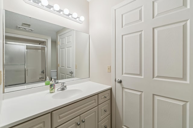 bathroom featuring vanity, toilet, and a shower with door