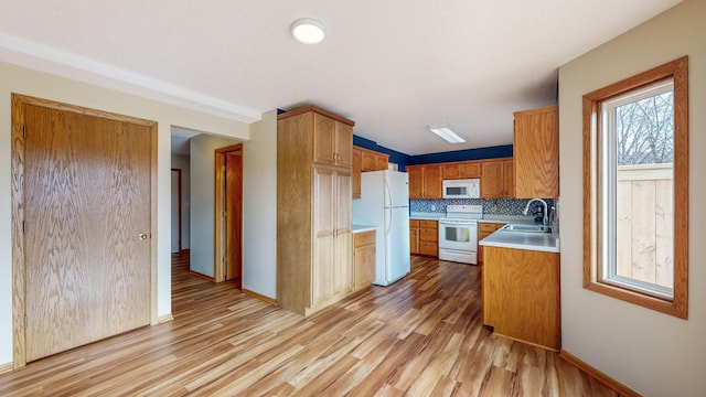 kitchen featuring sink, white appliances, light hardwood / wood-style flooring, and decorative backsplash