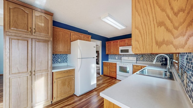 kitchen featuring sink, white appliances, tasteful backsplash, and light hardwood / wood-style floors