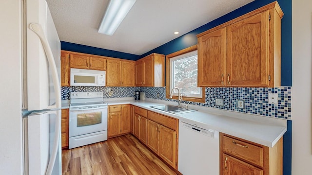 kitchen featuring sink, light wood-type flooring, white appliances, and decorative backsplash