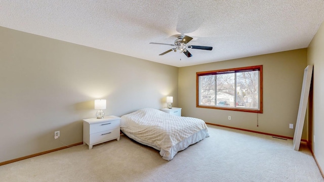 bedroom with ceiling fan, light colored carpet, and a textured ceiling