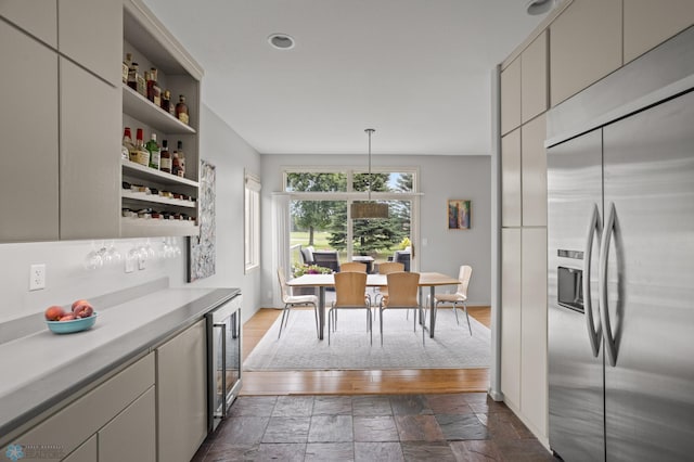 kitchen featuring stainless steel built in refrigerator, beverage cooler, and pendant lighting