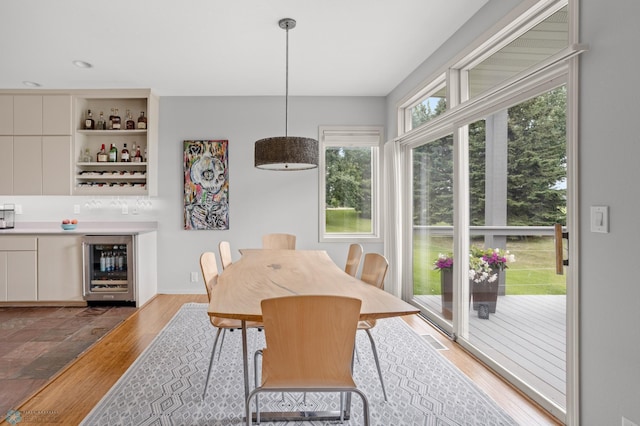 dining room featuring light hardwood / wood-style floors, beverage cooler, and bar area