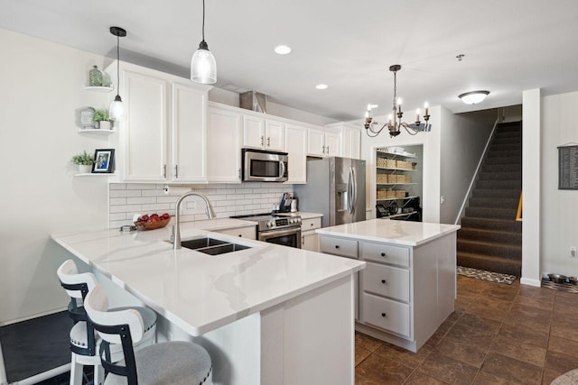 kitchen featuring white cabinets, decorative backsplash, stainless steel appliances, and hanging light fixtures