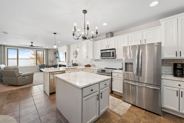 kitchen with pendant lighting, stainless steel appliances, white cabinetry, and a kitchen island