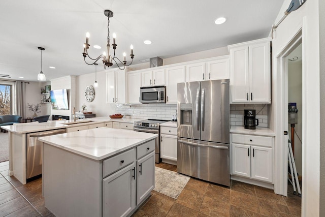 kitchen featuring white cabinets, decorative light fixtures, a center island, and stainless steel appliances