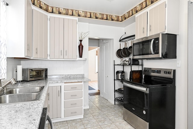 kitchen with tasteful backsplash, sink, stainless steel appliances, and white cabinets