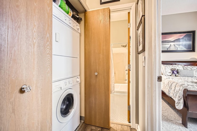 laundry room with hardwood / wood-style flooring and stacked washer / drying machine