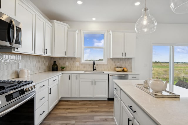 kitchen featuring hanging light fixtures, sink, appliances with stainless steel finishes, tasteful backsplash, and white cabinetry