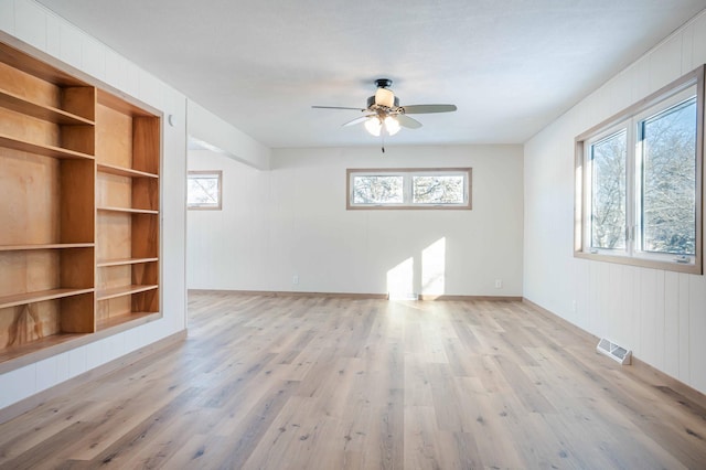 unfurnished living room featuring ceiling fan, built in features, and light hardwood / wood-style flooring