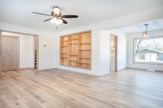 empty room with ceiling fan, light hardwood / wood-style floors, and built in features