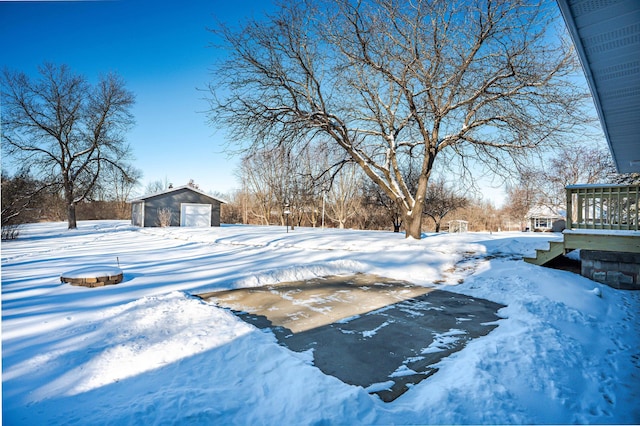 yard layered in snow featuring a garage and an outbuilding