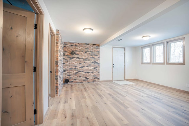 unfurnished room featuring brick wall and light hardwood / wood-style floors