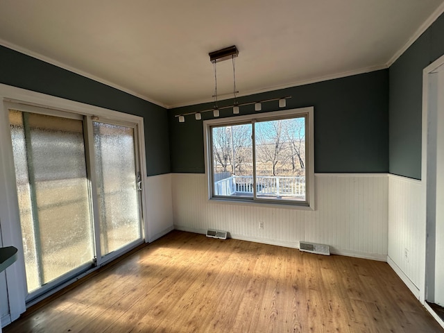 unfurnished dining area with light wood-type flooring and ornamental molding