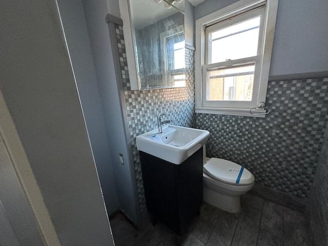 bathroom featuring vanity, toilet, and tile walls