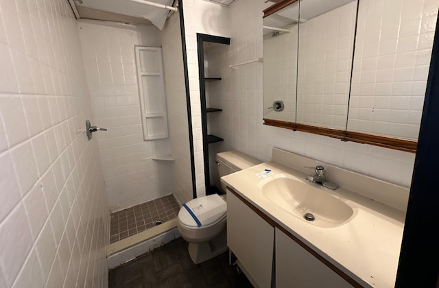 bathroom featuring a tile shower, parquet flooring, toilet, vanity, and tile walls