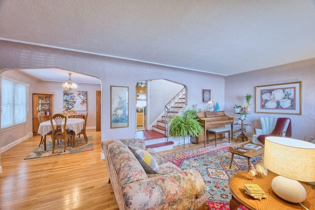 living room with a chandelier, light wood-type flooring, and a textured ceiling