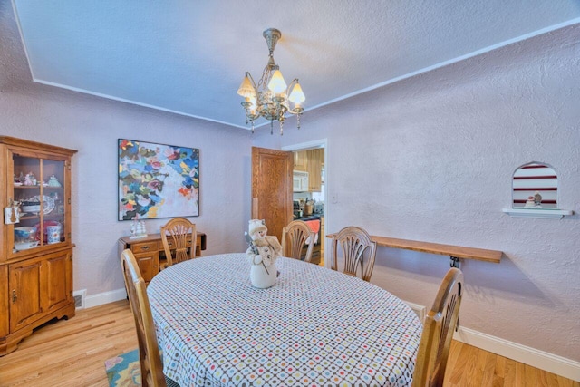 dining area with light hardwood / wood-style floors and an inviting chandelier